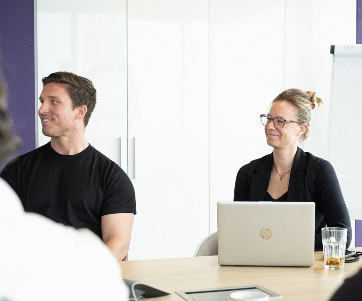 Two people smiling during a meeting in a modern office setting.